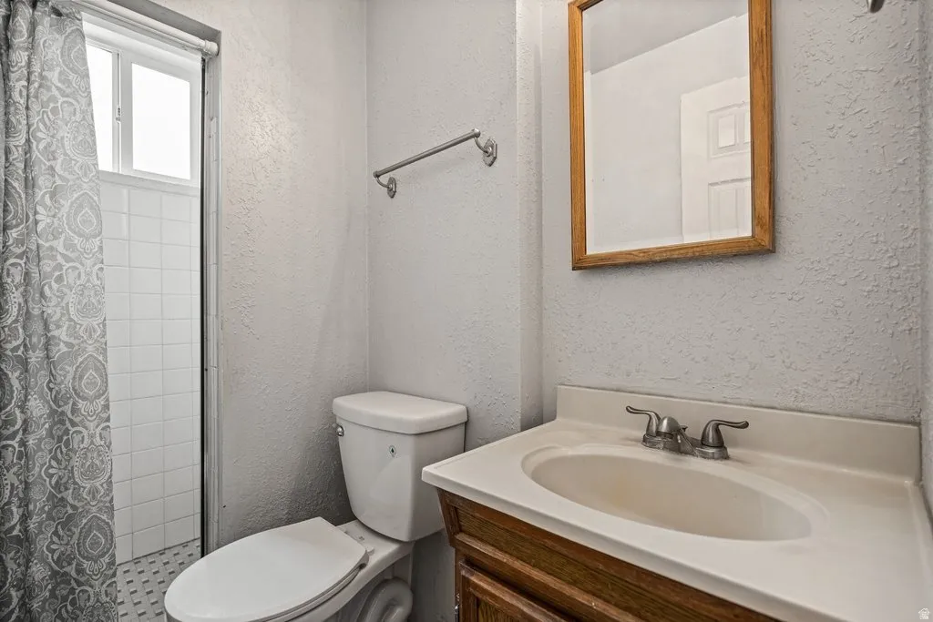 Full bath featuring vanity, a textured wall, and curtained shower