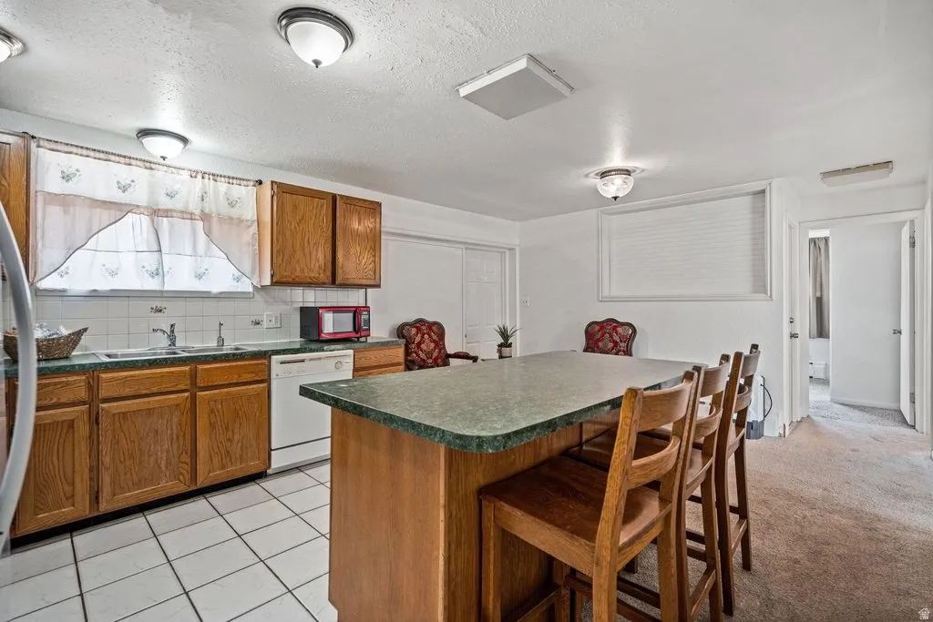 Kitchen with wood finish cabinetry, dark countertops, tasteful backsplash, a breakfast bar area, and a textured ceiling