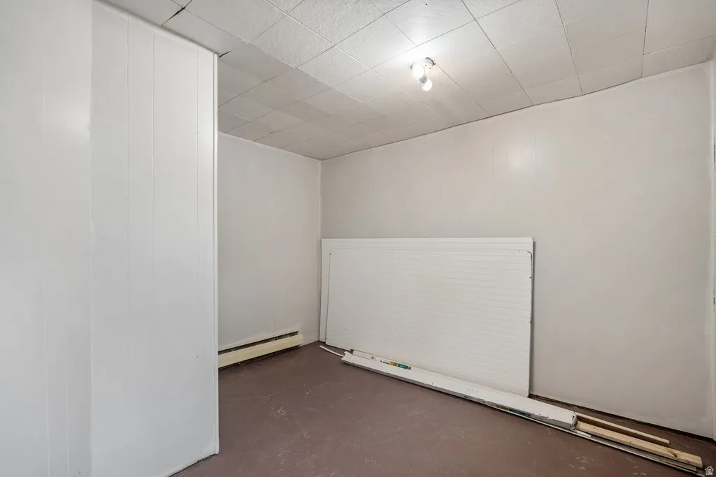 Spare room featuring finished concrete flooring and a baseboard heating unit