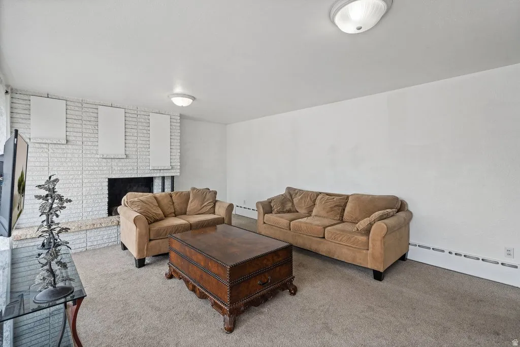 Carpeted living area featuring baseboard heating and a fireplace