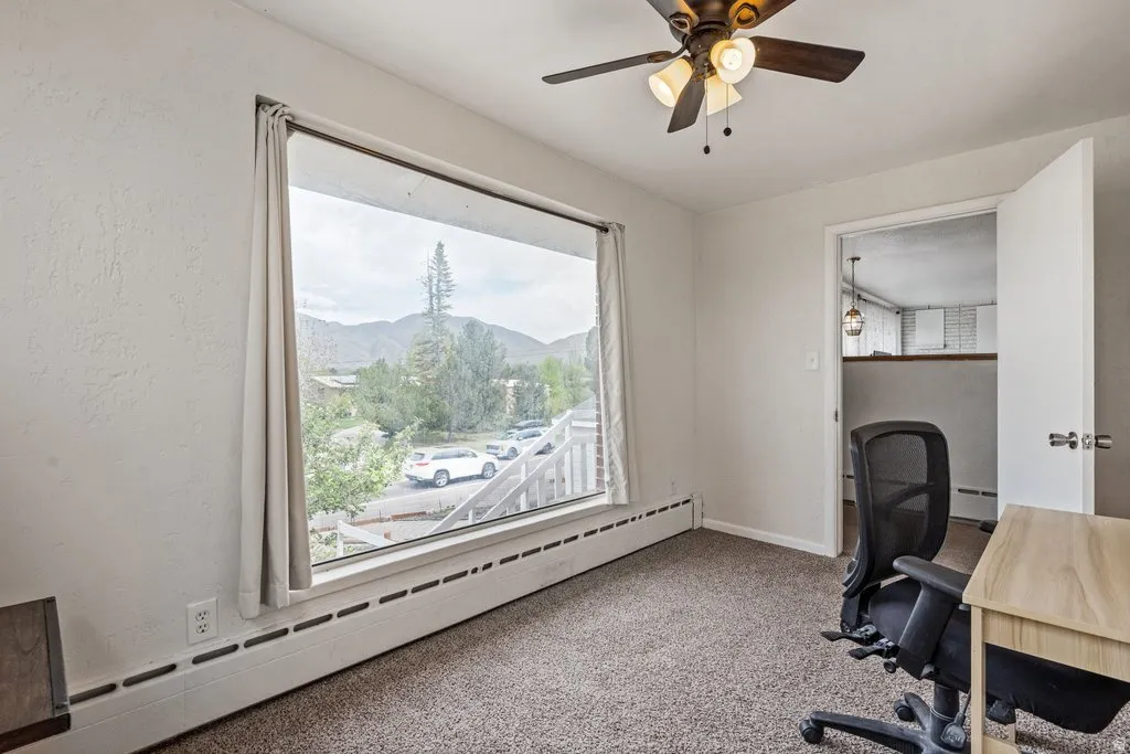 Home office featuring baseboard heating, a mountain view, carpet flooring, and ceiling fan