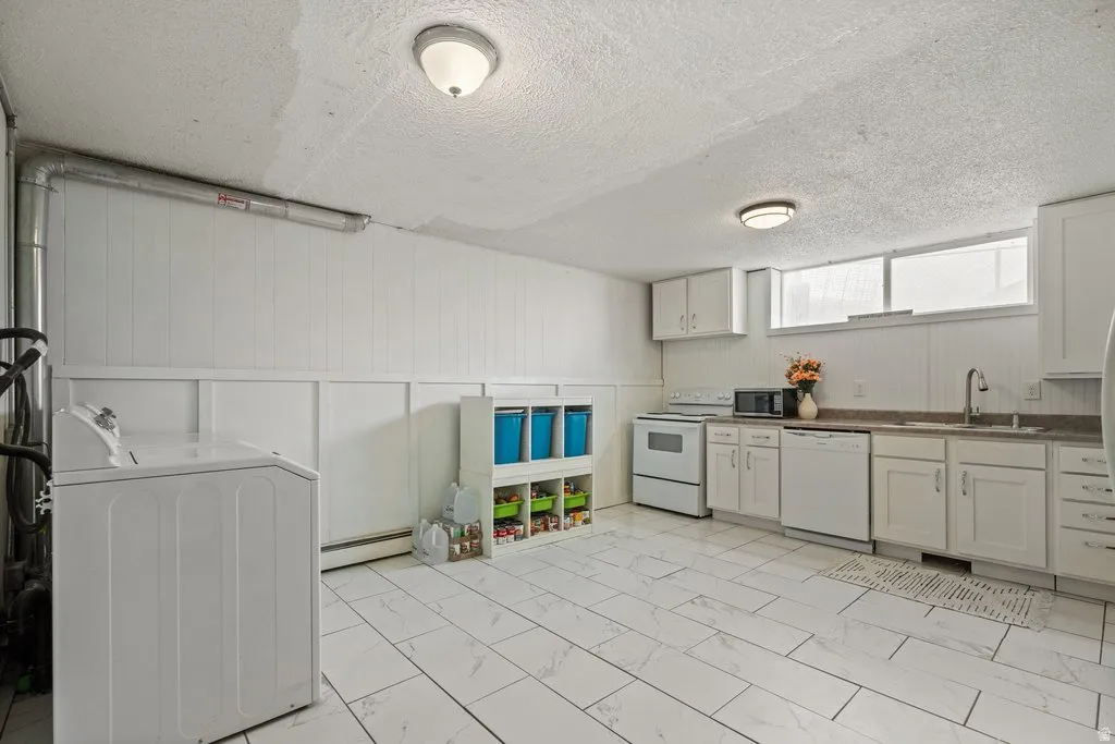 Kitchen with washer / clothes dryer, white appliances, dark countertops, a textured ceiling, and light marble finish floors
