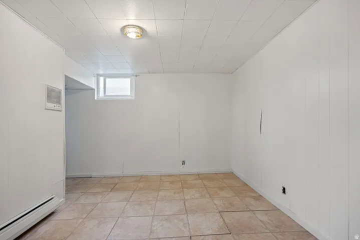 Basement featuring baseboard heating and light tile patterned floors