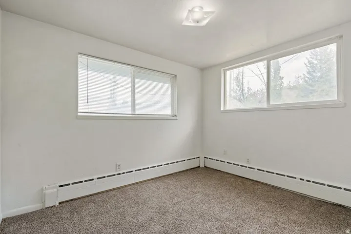 Carpeted empty room with a baseboard radiator