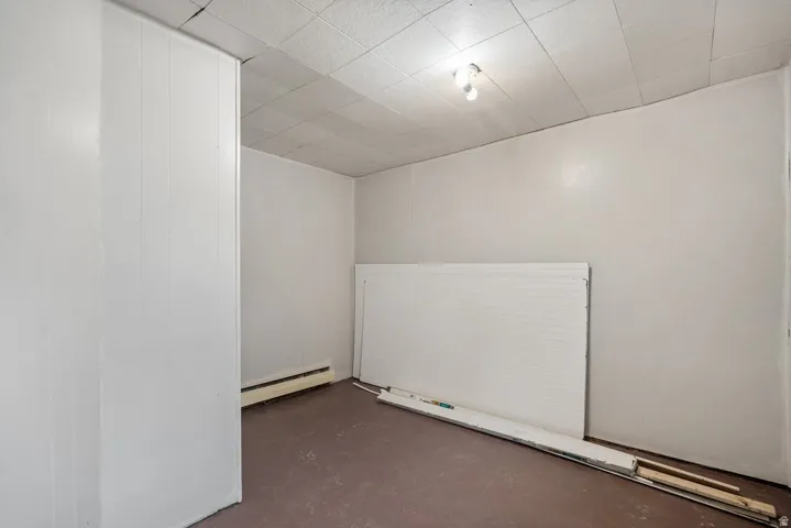 Spare room featuring finished concrete flooring and a baseboard heating unit