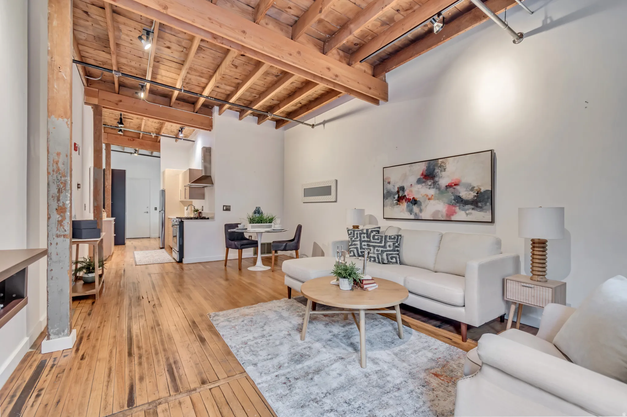 Living area featuring rail lighting, a wood ceiling with exposed beams, and light wood-style flooring