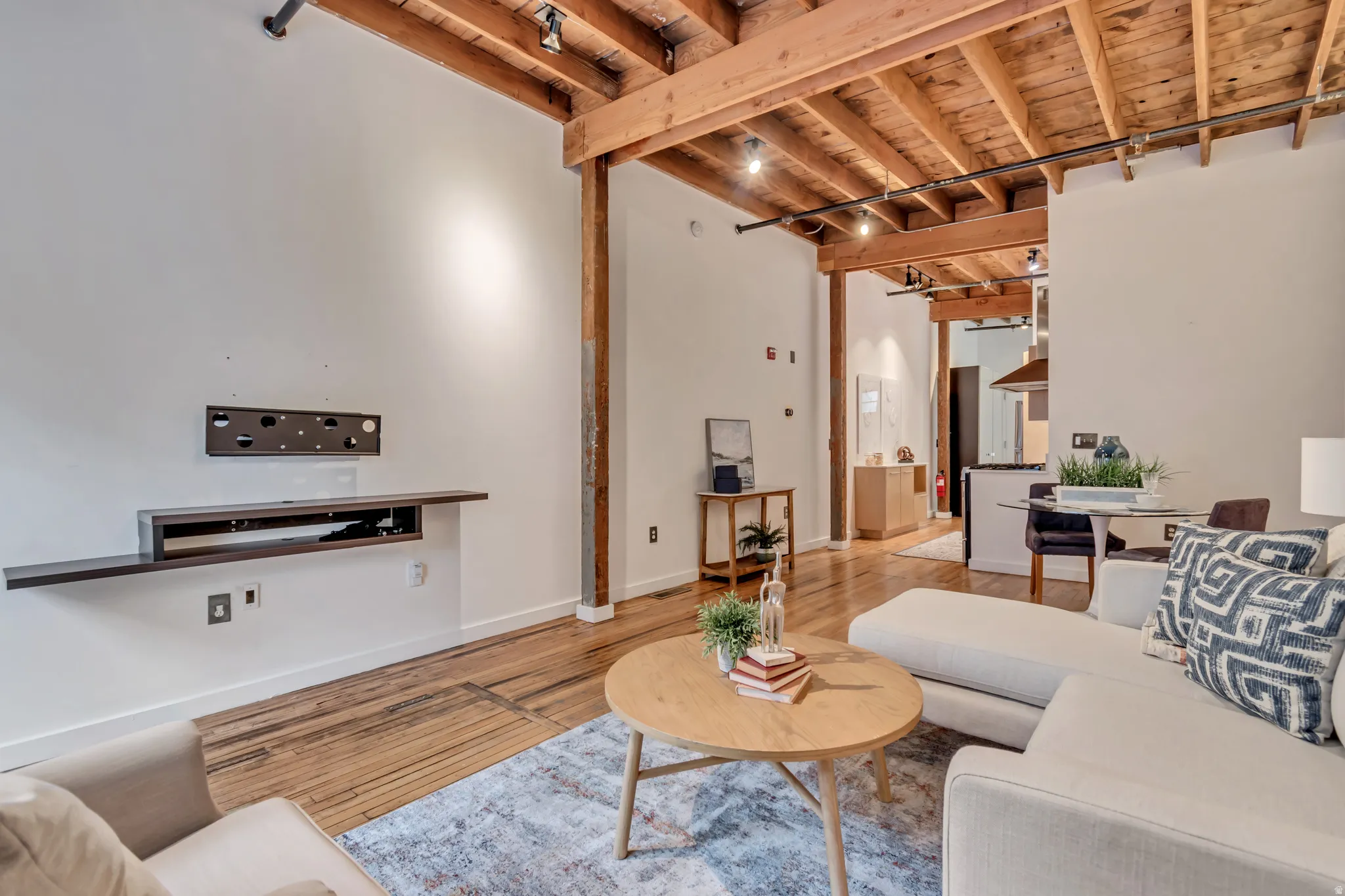 Living room with rail lighting, a high wooden beamed ceiling, and wood finished floors