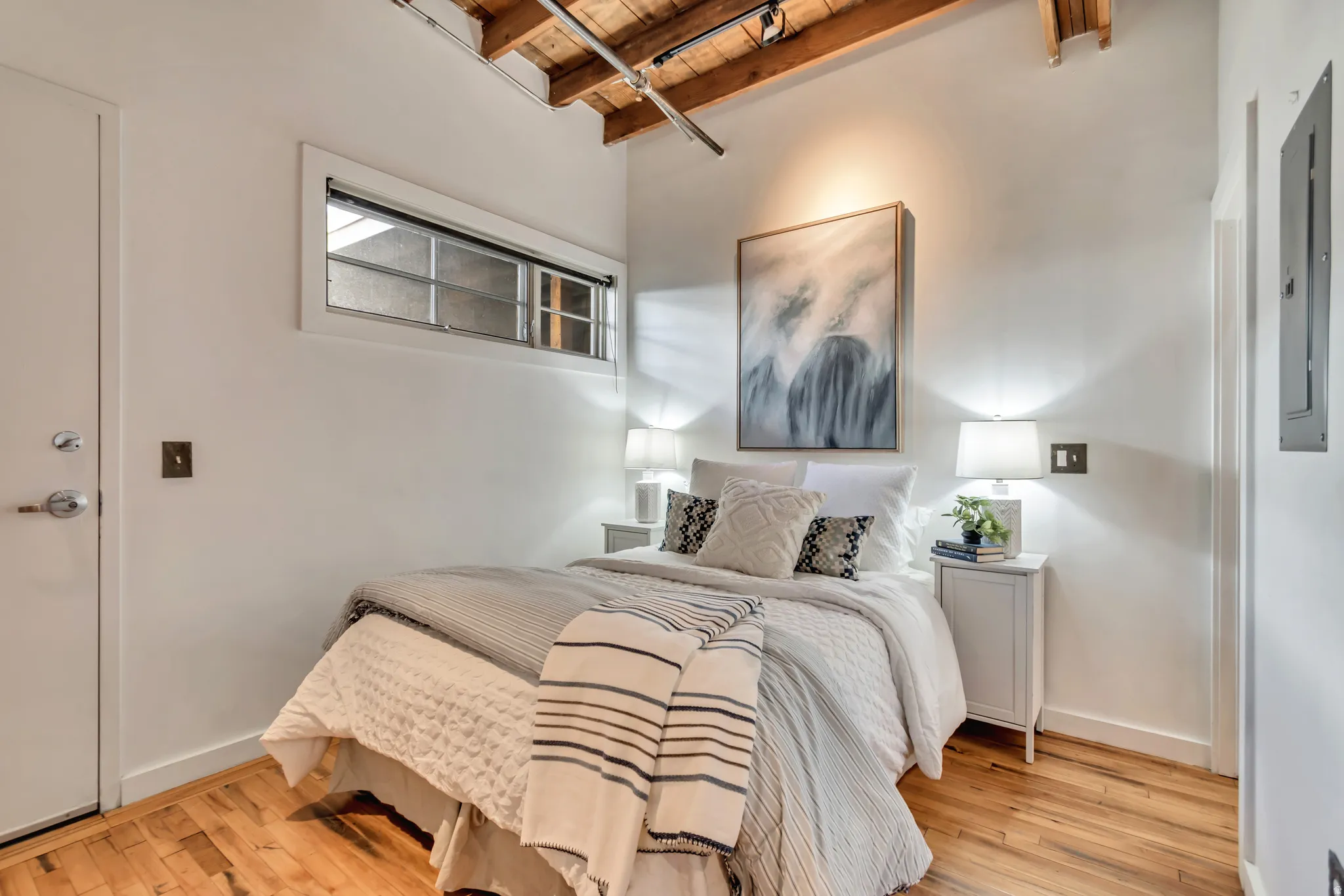 Bedroom featuring a wooden ceiling with exposed beams, light wood finished floors, track lighting, and electric panel