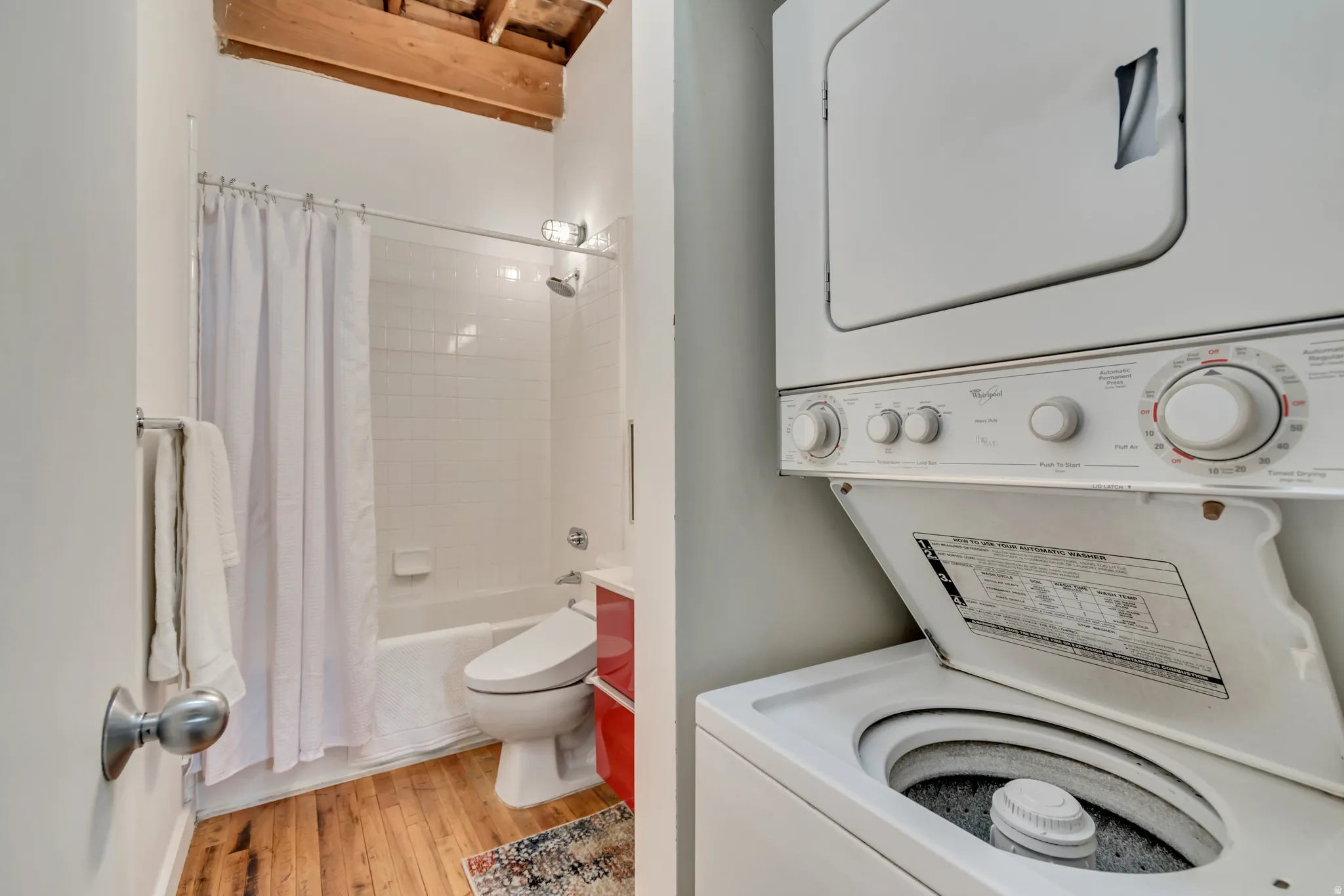 Laundry room featuring light wood-style floors and stacked washer / dryer