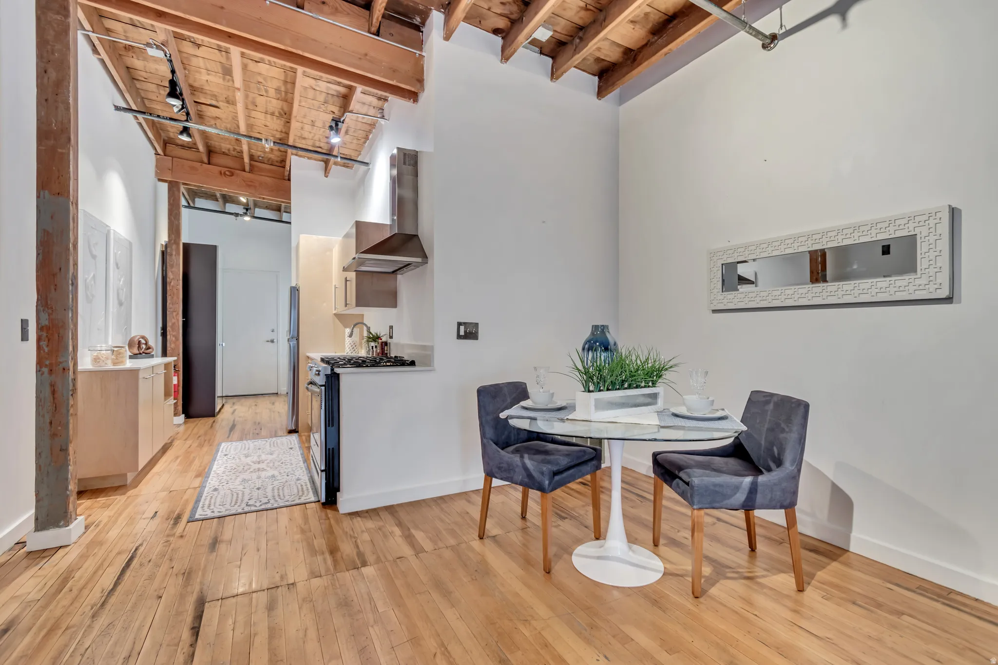 Dining space with a high wood beamed ceiling, light wood-style floors, and rail lighting