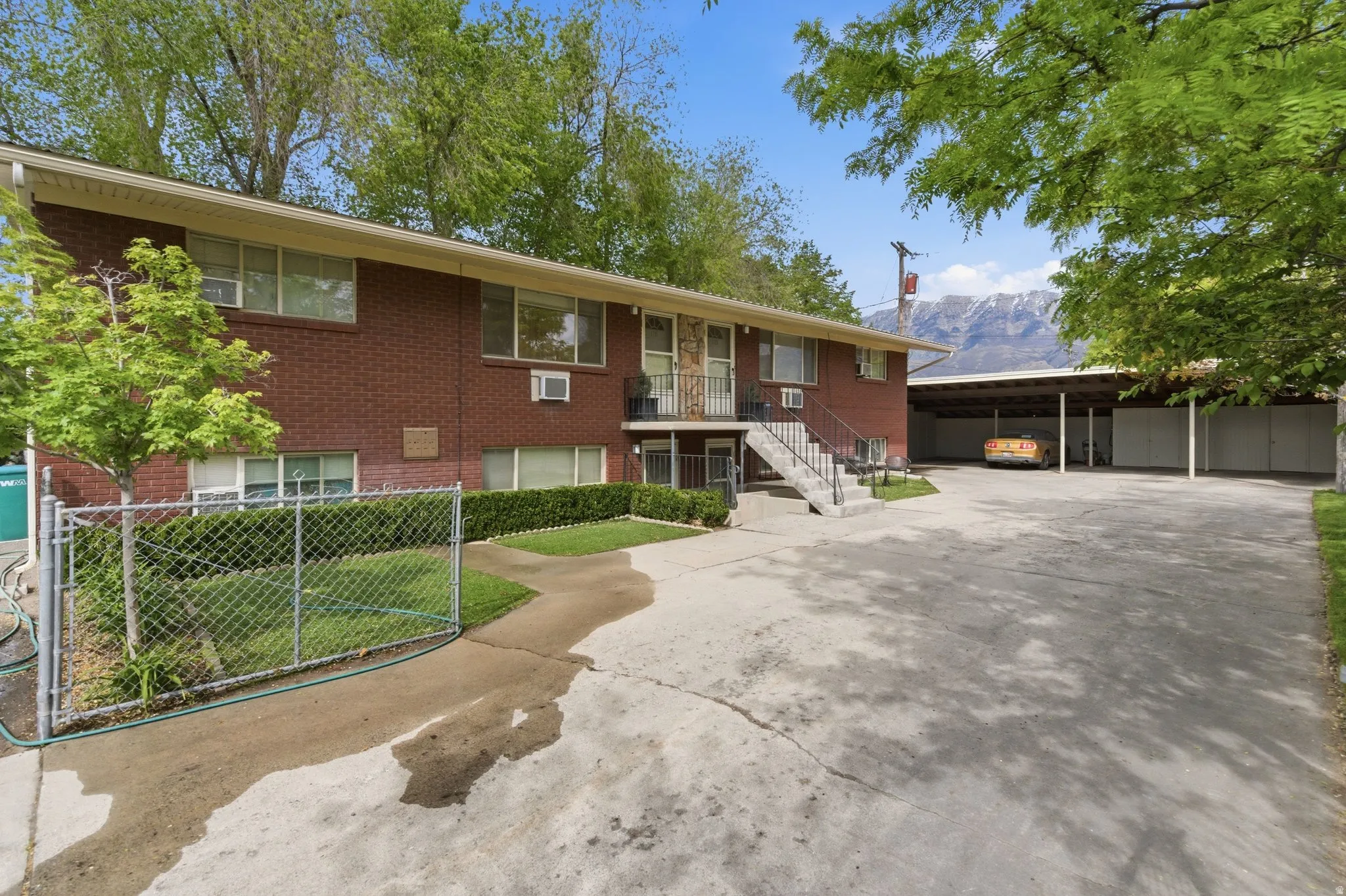 View of front of property with brick siding, concrete driveway, a mountain view, and an attached carport