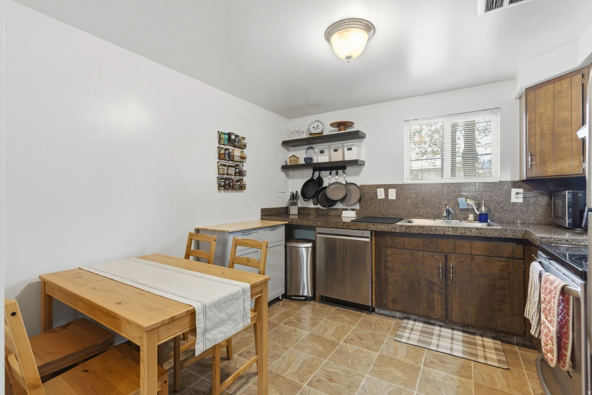Kitchen featuring tile countertops, stainless steel appliances, dark wood finish cabinets, tasteful backsplash, and open shelves