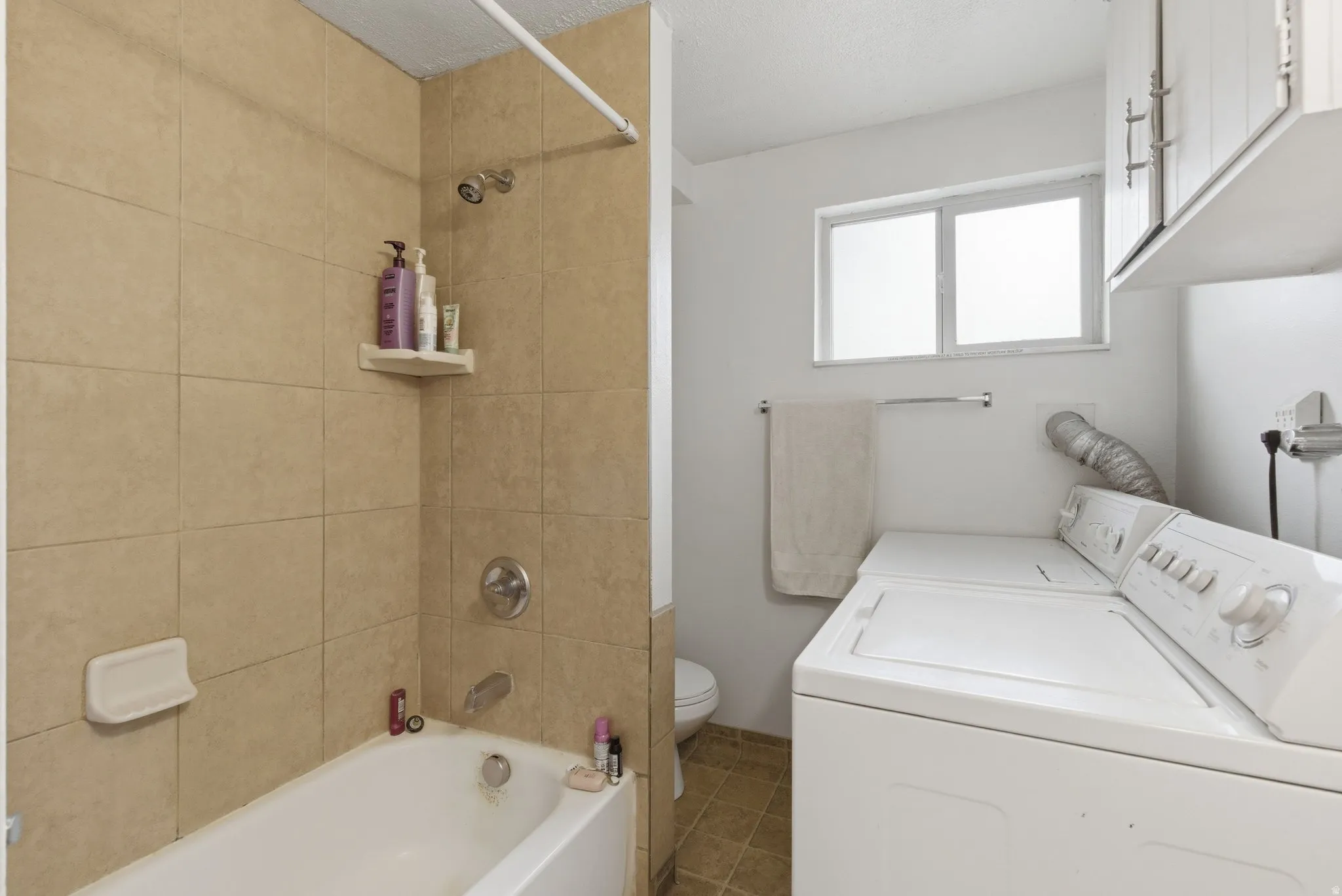 Full bathroom featuring vanity, tub / shower combination, washer and clothes dryer, a textured ceiling, and tile patterned floors