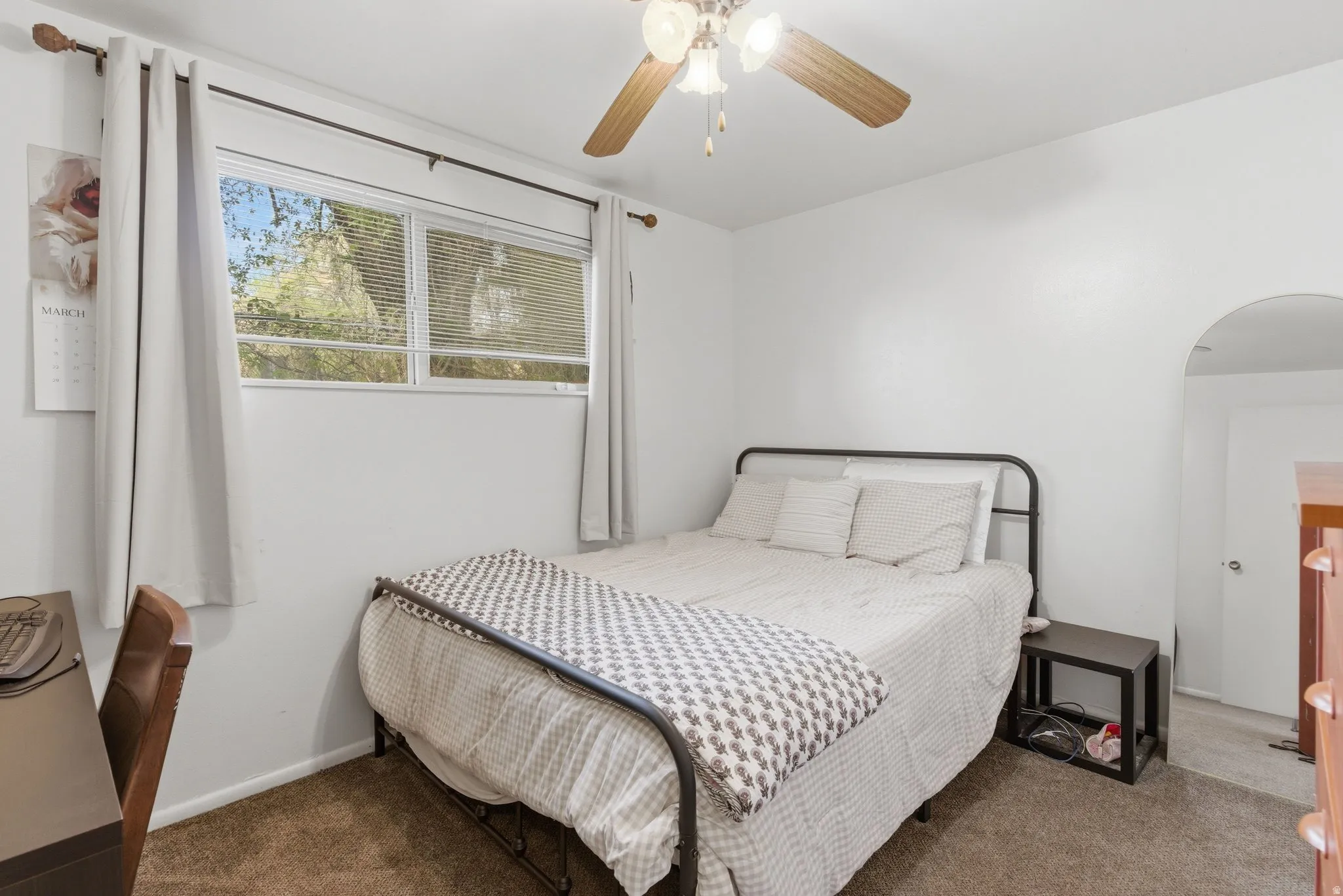 Bedroom with dark colored carpet, a ceiling fan, and arched walkways