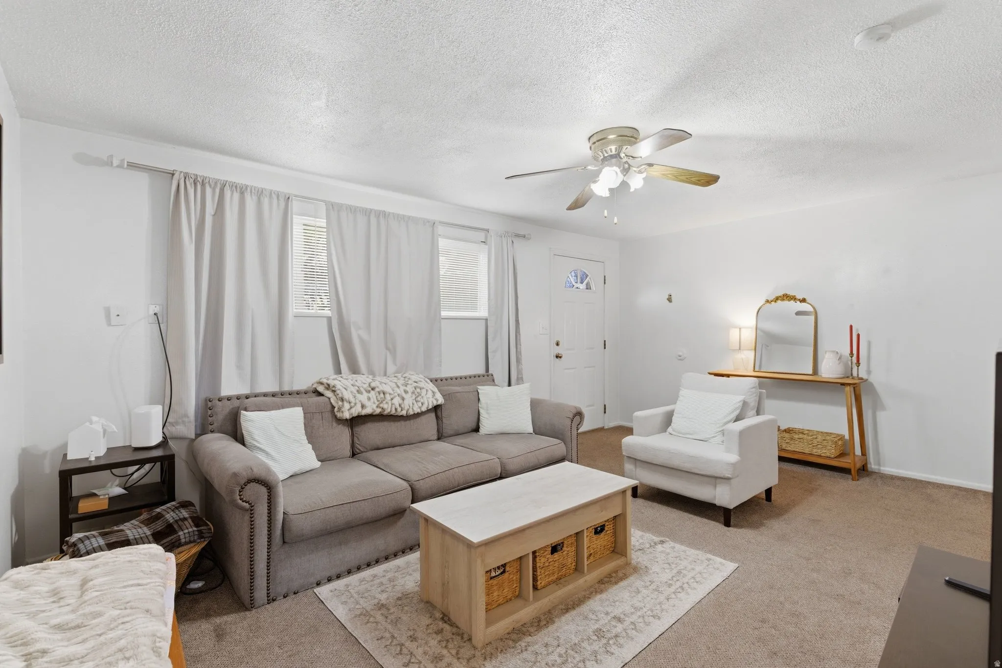 Living area with carpet flooring, ceiling fan, and a textured ceiling