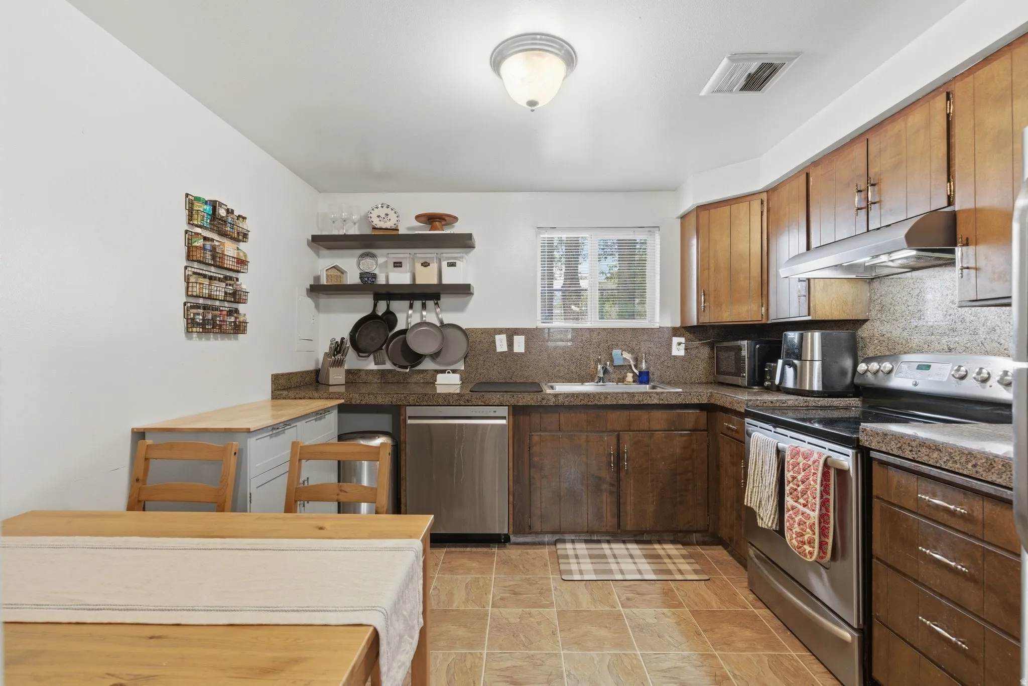 Kitchen with stainless steel appliances, tasteful backsplash, and open shelves