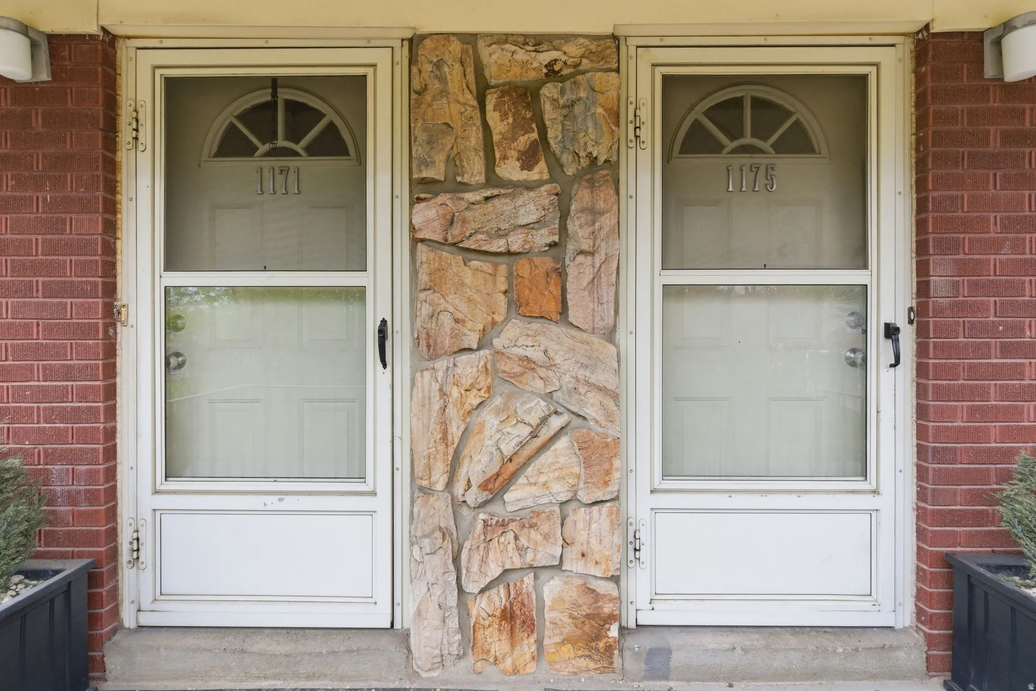 View of exterior entry with stone siding and brick siding