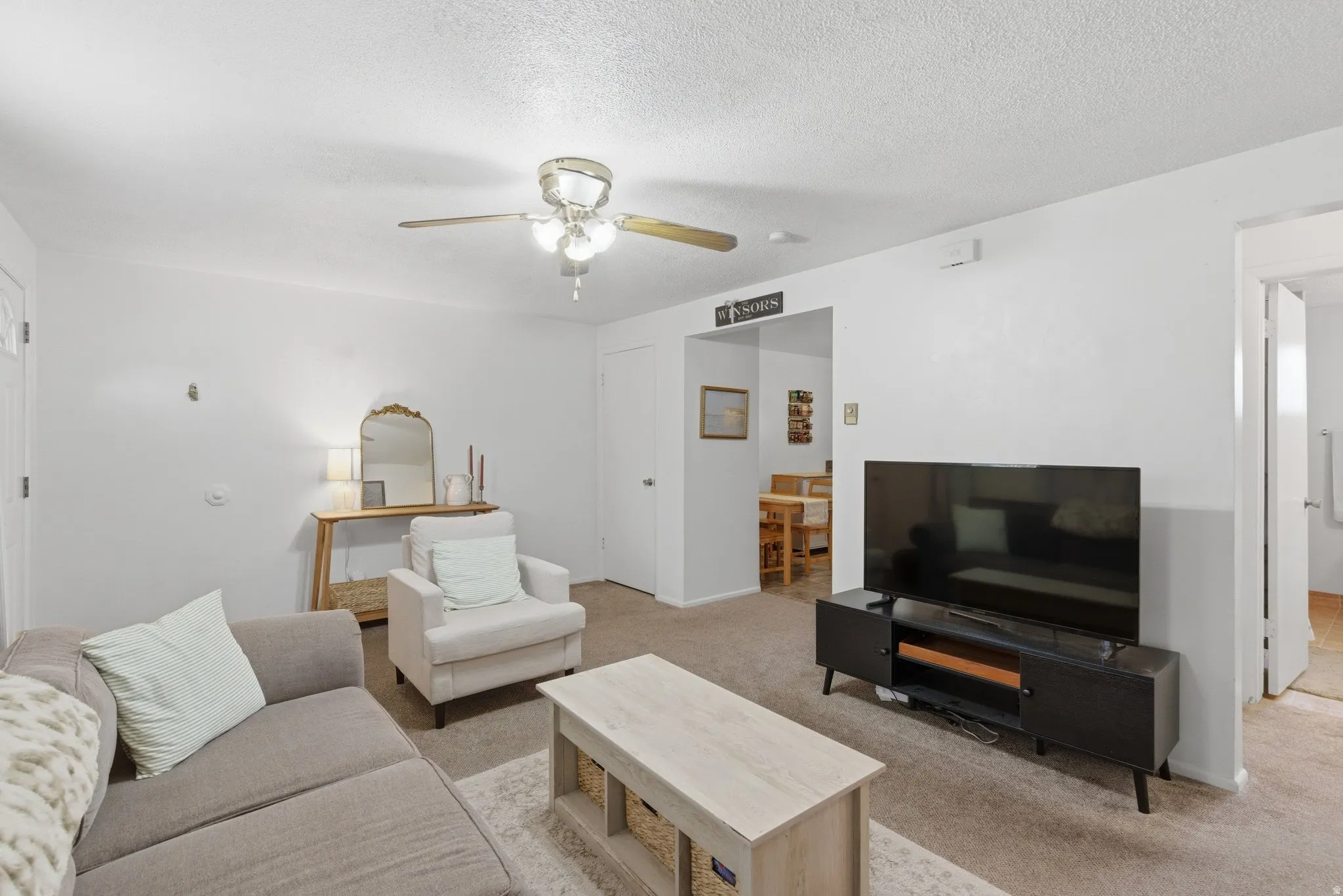 Living room featuring light colored carpet, ceiling fan, and a textured ceiling