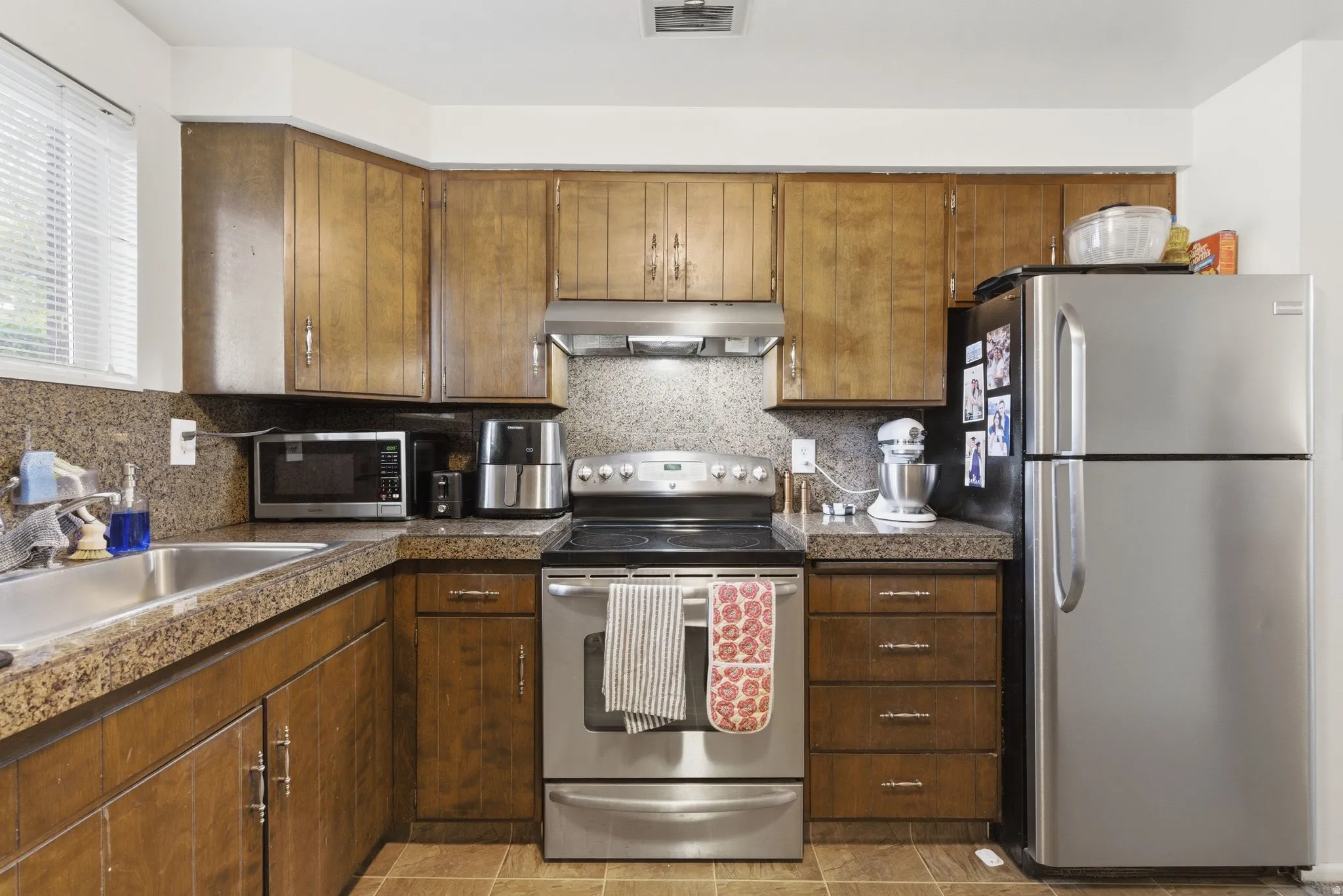 Kitchen with stainless steel appliances, tile countertops, and tasteful backsplash