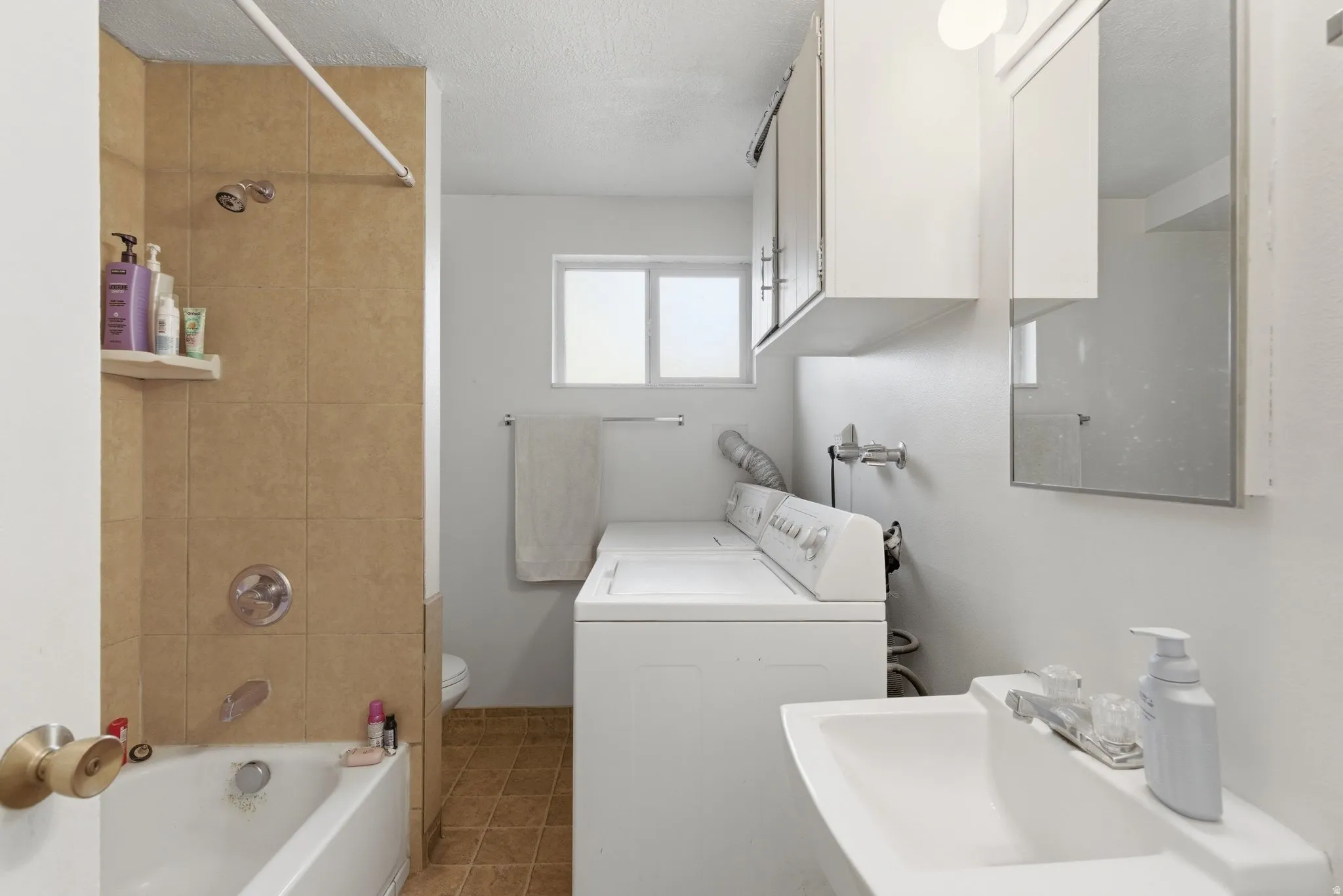 Full bath featuring shower / tub combination, a textured ceiling, and washer and clothes dryer