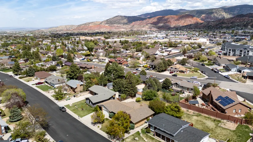 Aerial view of property and surrounding area featuring a mountain backdrop and nearby suburban area
