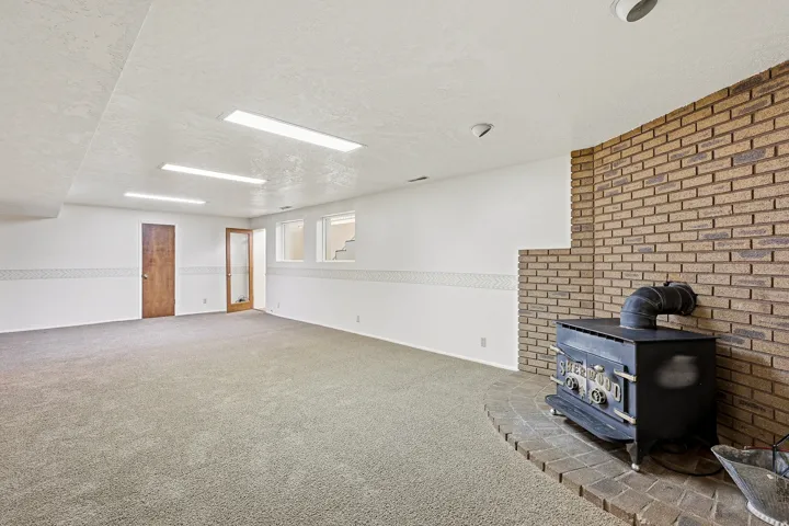 Below grade area with a wood stove, carpet floors, a textured ceiling, and brick wall