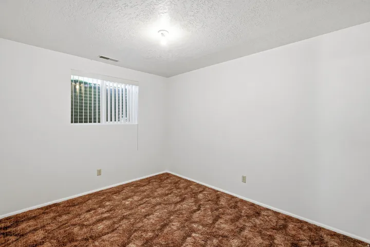 Unfurnished room featuring a textured ceiling and dark carpet