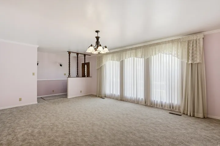 Spare room featuring crown molding, carpet flooring, and a chandelier