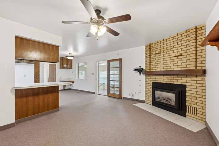 Unfurnished living room with light colored carpet, a ceiling fan, and a fireplace