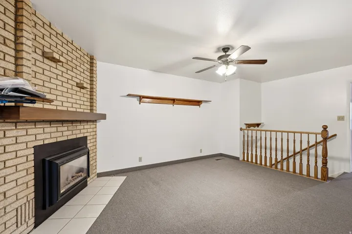 Unfurnished living room featuring carpet floors, a fireplace, and ceiling fan