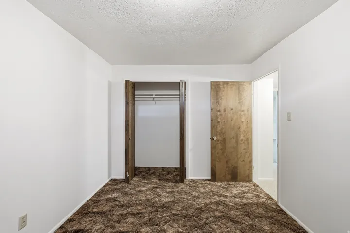 Unfurnished bedroom with dark carpet, a closet, and a textured ceiling