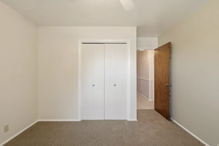 Unfurnished bedroom featuring carpet, a closet, and a ceiling fan