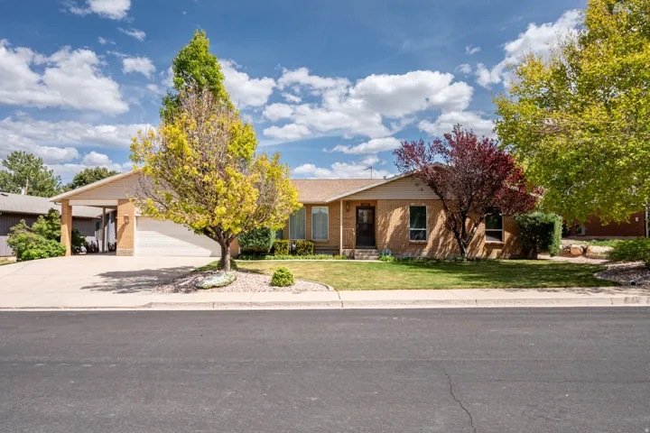 View of front of house featuring a front yard, concrete driveway, brick siding, an attached garage, and covered porch