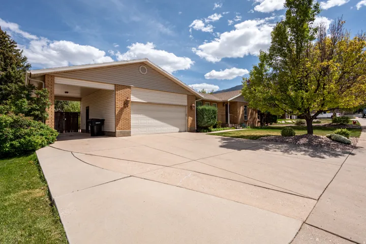 View of front of home featuring brick siding, driveway, an attached garage, a front yard, and an attached carport