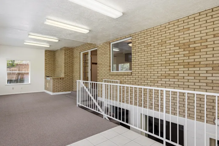 Unfurnished room featuring brick wall, a textured ceiling, and carpet flooring