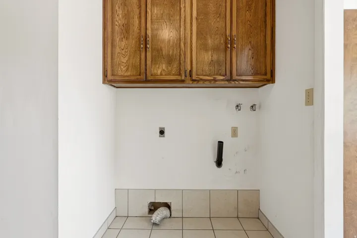 Laundry area featuring hookup for an electric dryer, cabinet space, light tile patterned flooring, and hookup for a washing machine