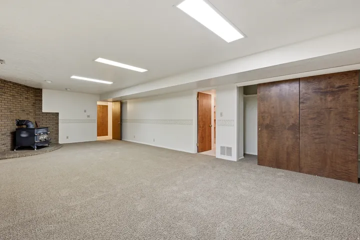 Finished basement featuring a wood stove and carpet flooring