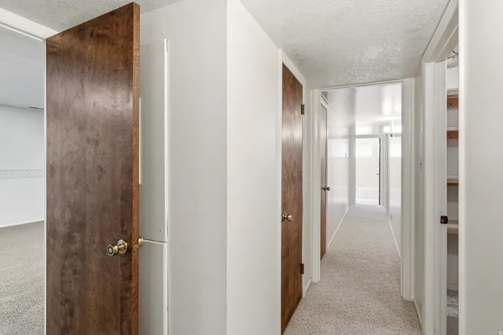 Hall with light colored carpet and a textured ceiling