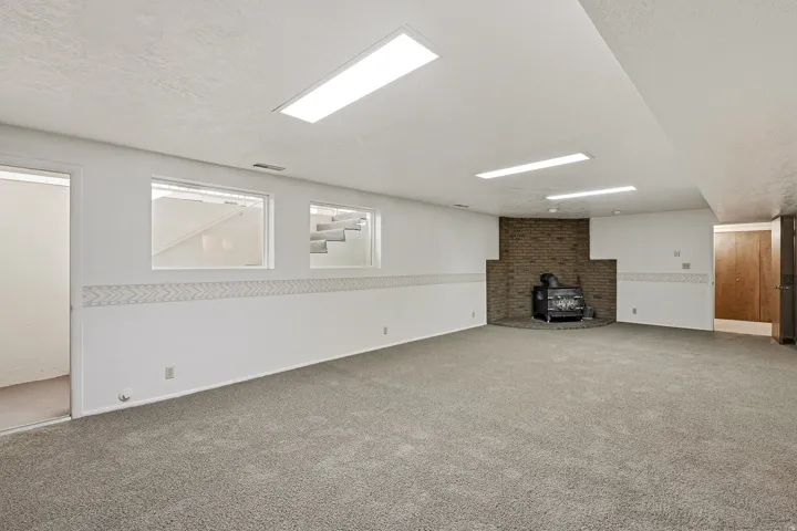 Unfurnished living room with a wood stove, carpet floors, and a textured ceiling