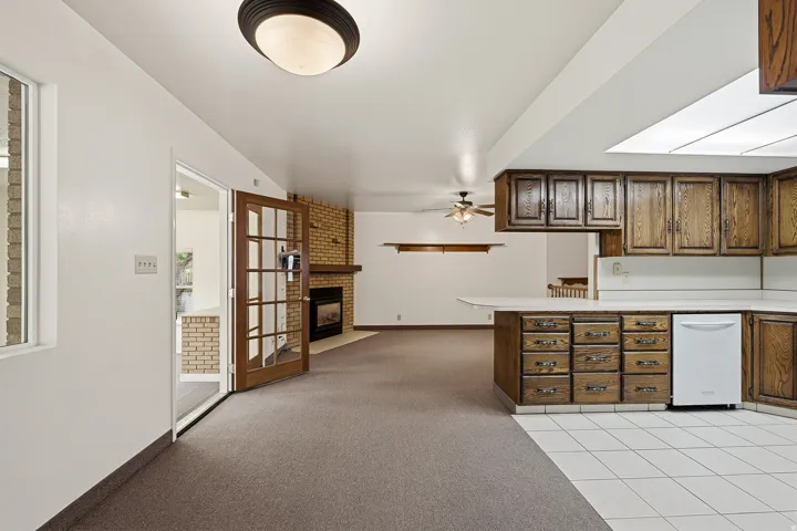 Kitchen featuring light countertops, a fireplace, a peninsula, and light colored carpet