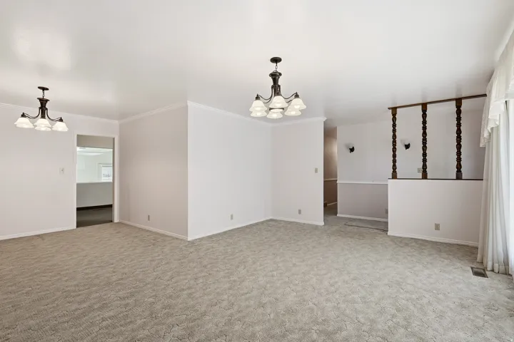 Carpeted empty room with a chandelier and crown molding