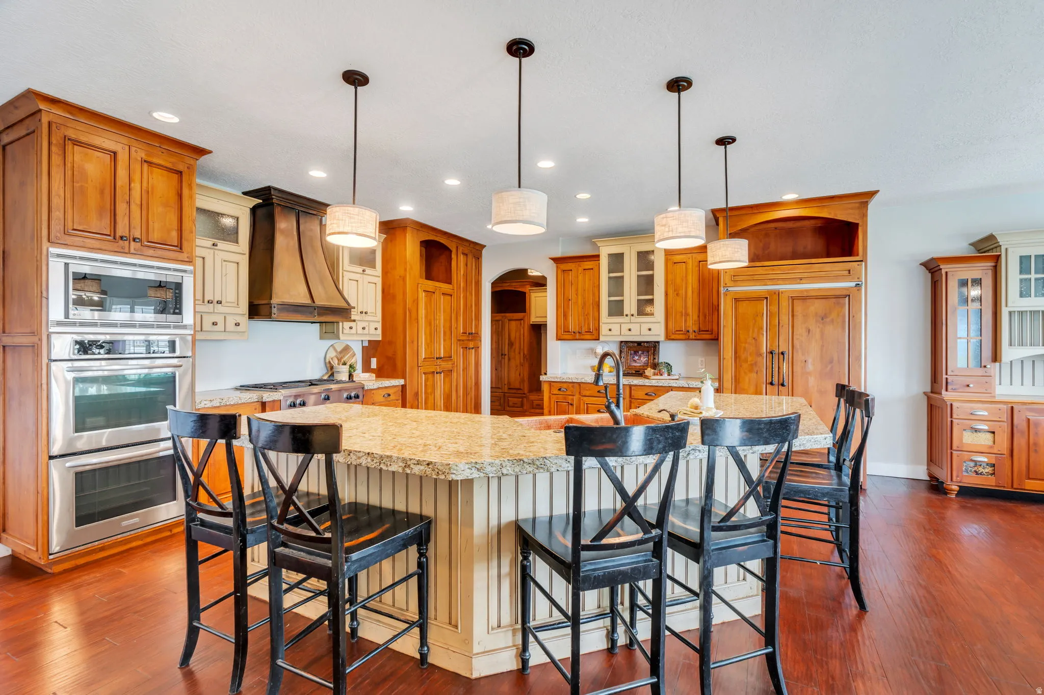Kitchen with glass fronted cabinets, stainless steel appliances, arched walkways, and dark wood-style floors
