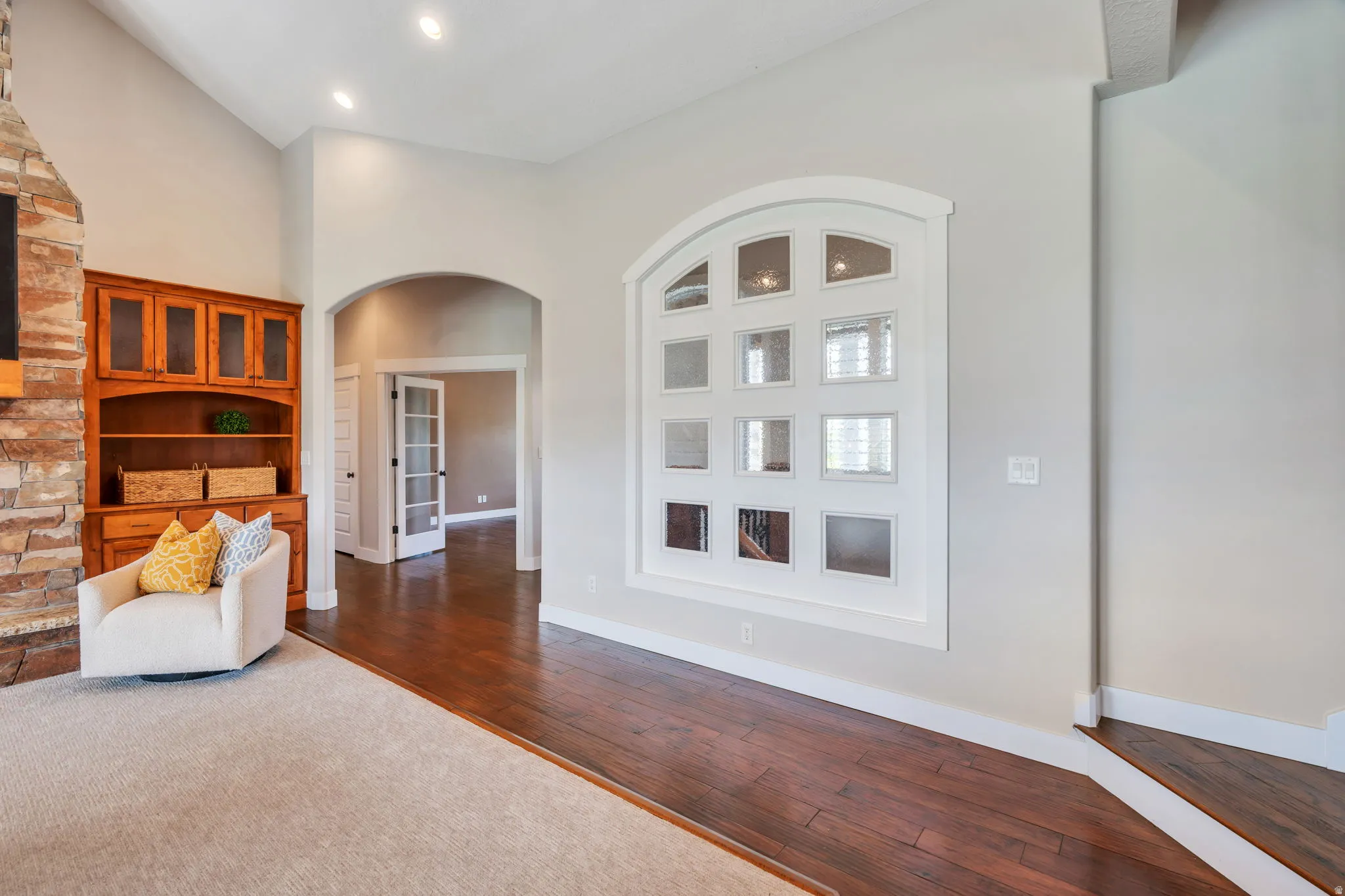 Living area featuring arched walkways, a high ceiling, dark wood-style flooring, and recessed lighting