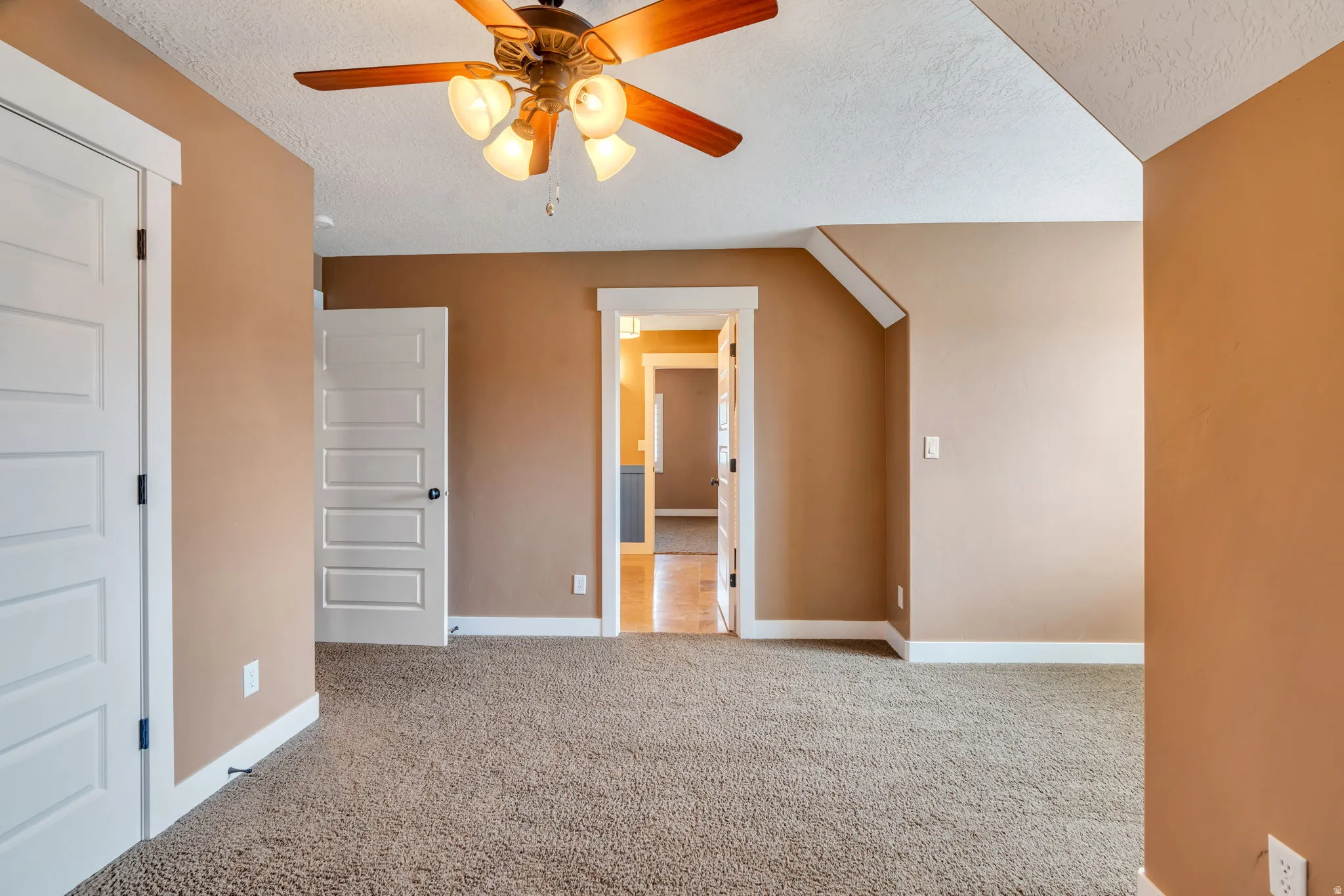Unfurnished bedroom featuring a textured ceiling, light colored carpet, and ceiling fan