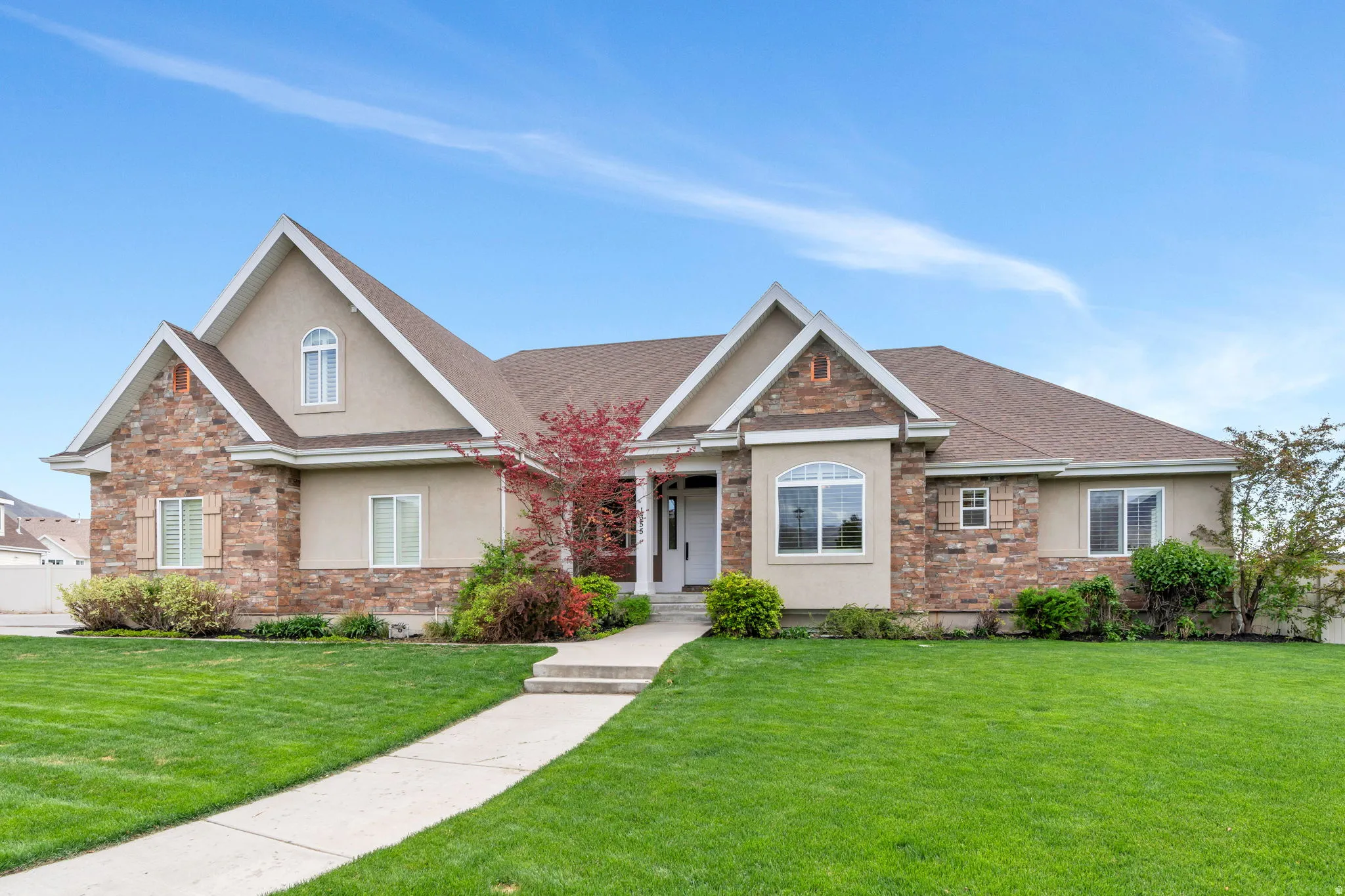 View of front of property featuring stucco siding, a front yard, stone siding, and a shingled roof