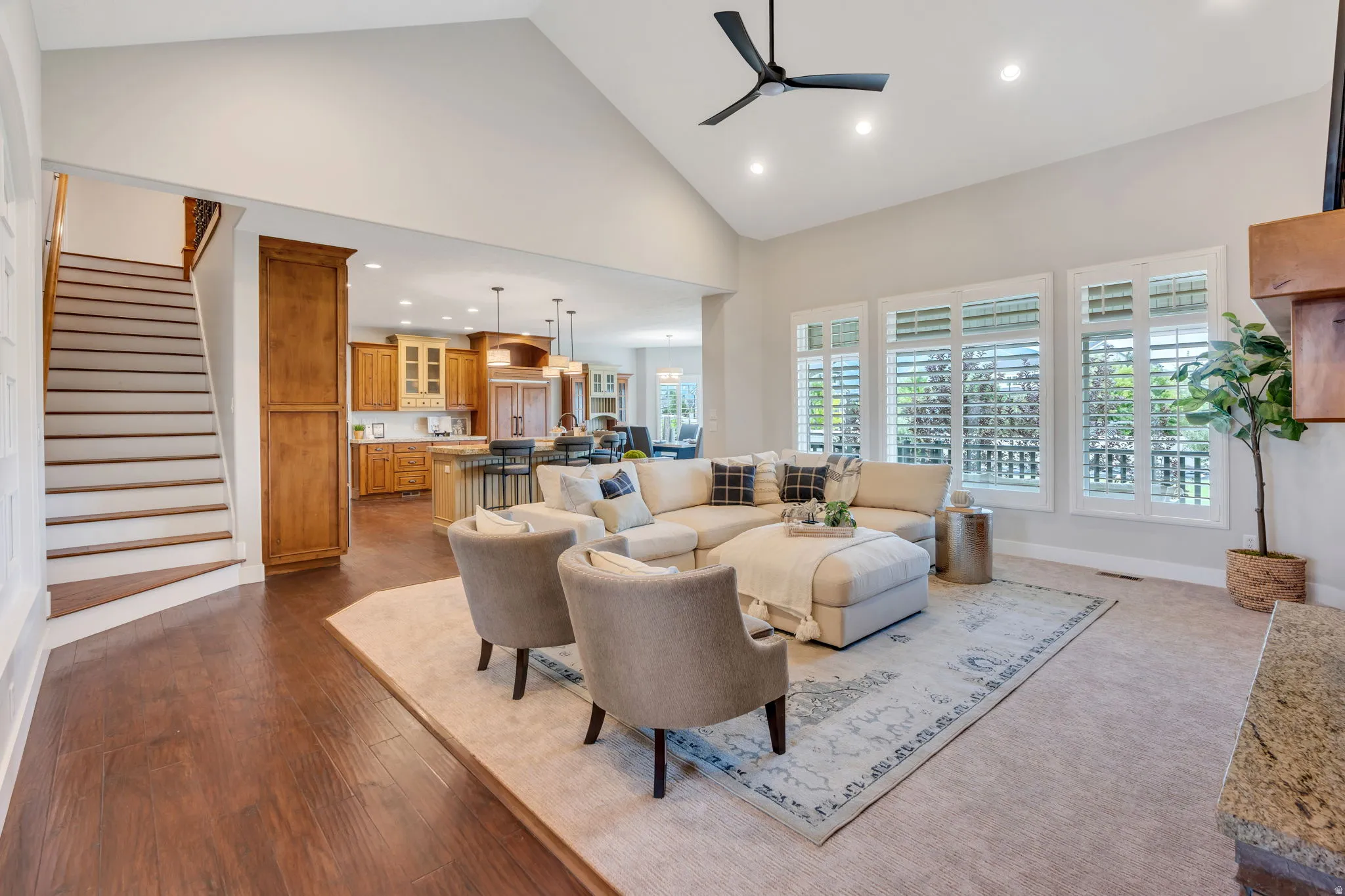 Open-concept living space featuring vaulted ceilings, wood-finish flooring, and a contemporary ceiling fan
