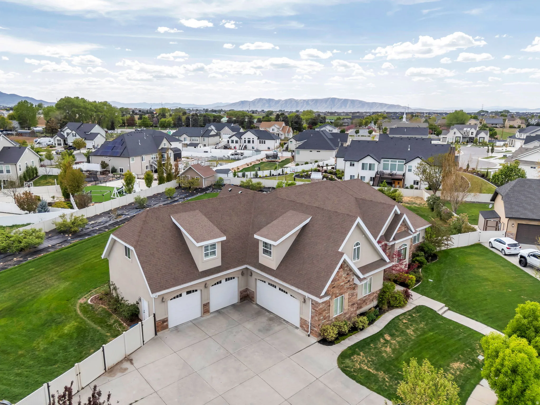 Expansive residential property featuring a multi-car driveway, three garage bays, and a stone and stucco exterior