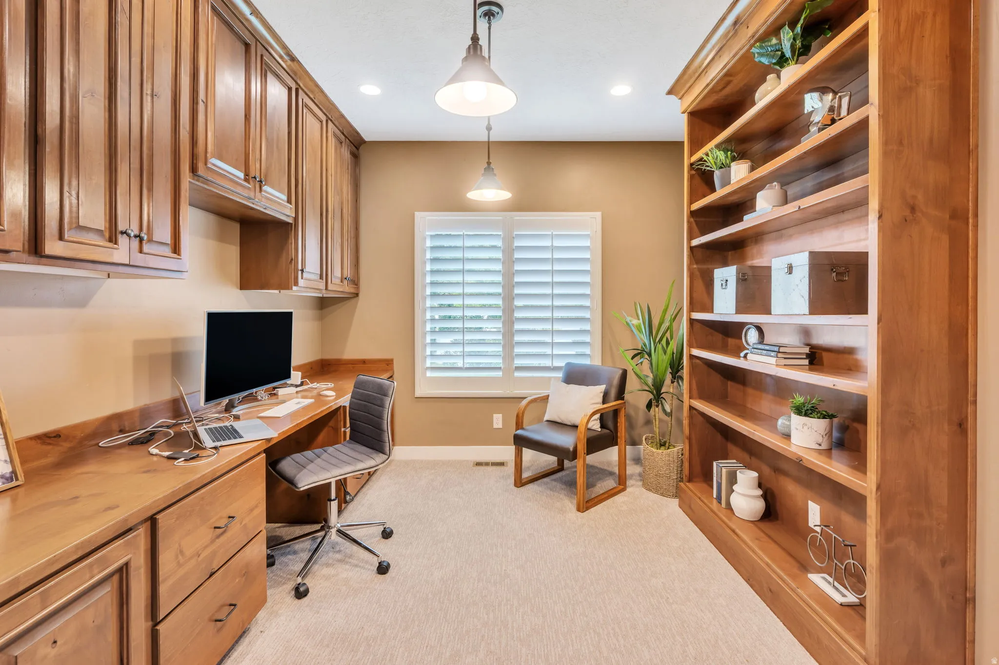 Dedicated workspace featuring extensive built-in cabinetry, a built-in desk with a wood-finish surface, and a full-height built-in bookcase