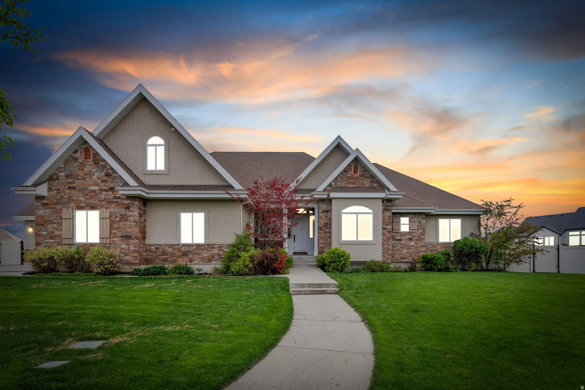 View of front of home featuring stone siding, stucco siding, and a lawn