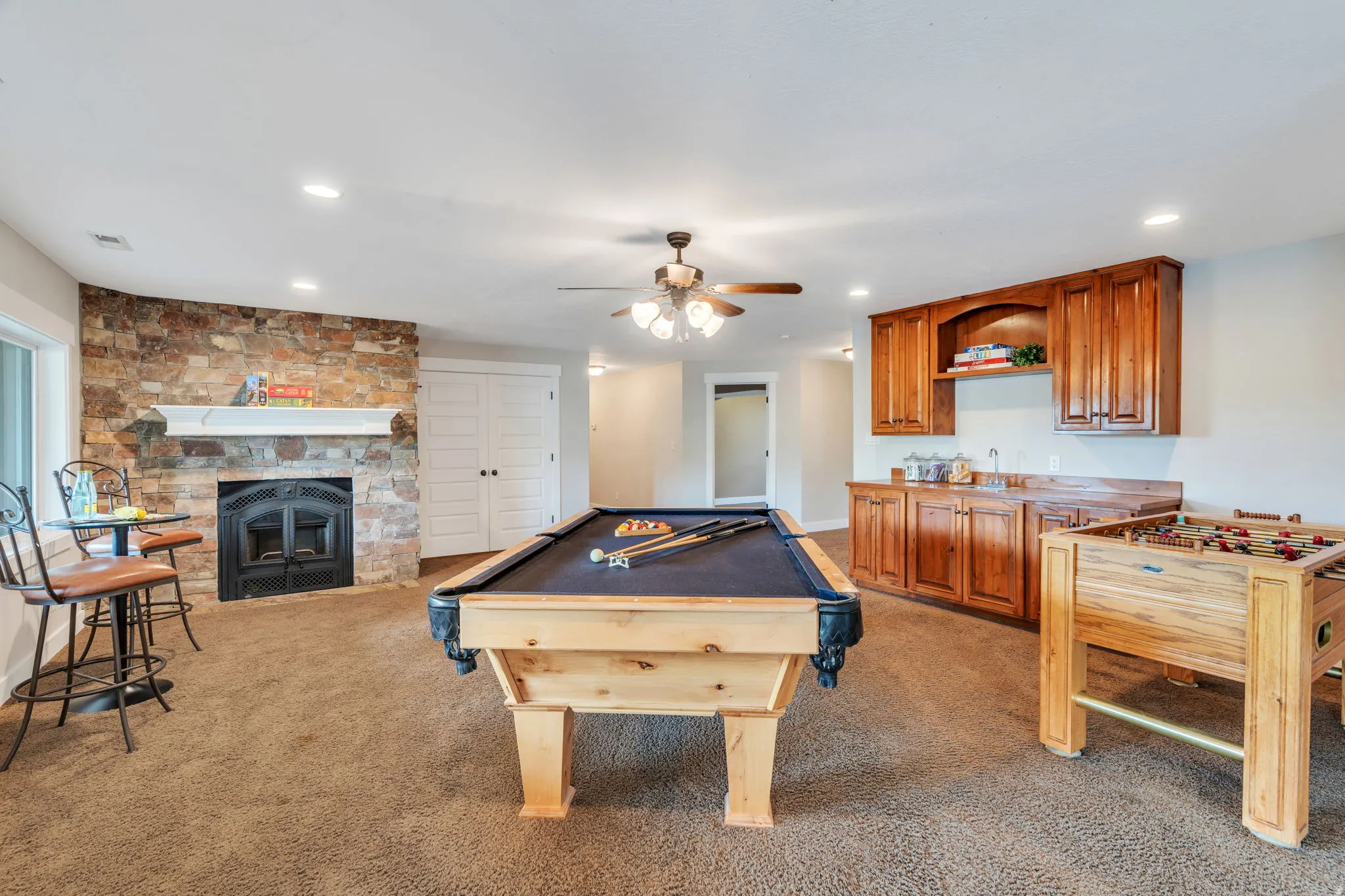 Game room with a ceiling fan, billiards table, a stone fireplace, recessed lighting, and light colored carpet